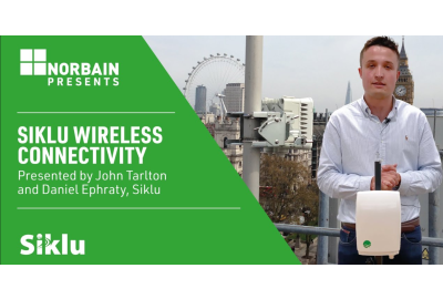 Man with Siklu Multihaul device with London in the background and a half of the picture is green with white text that says Siklu wireless connectivity